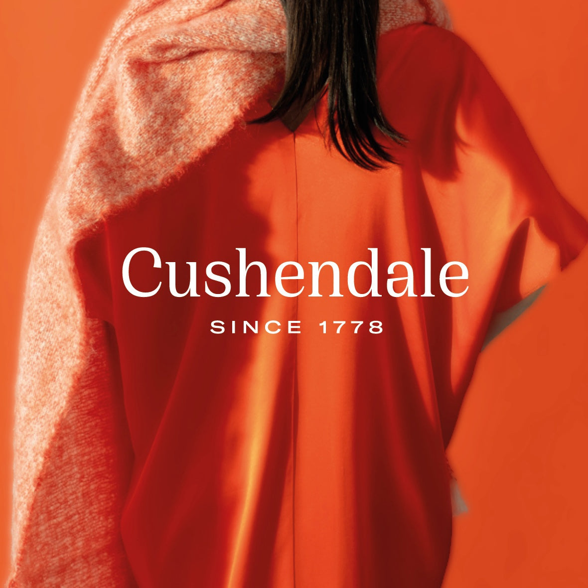 An orange Cushendale scarf wrapped on the shoulders of a model.