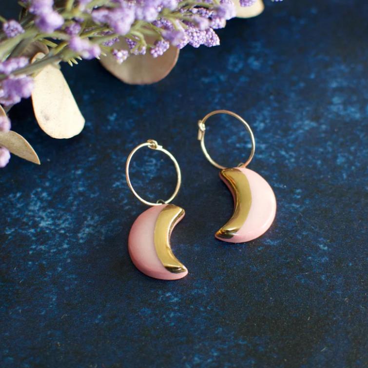 An image of pink moon Danu earring against a navy velvet background