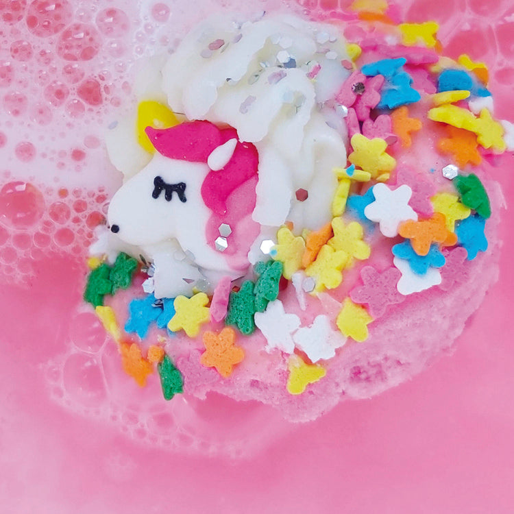 A pink unicorn bath blaster fizzing in water.